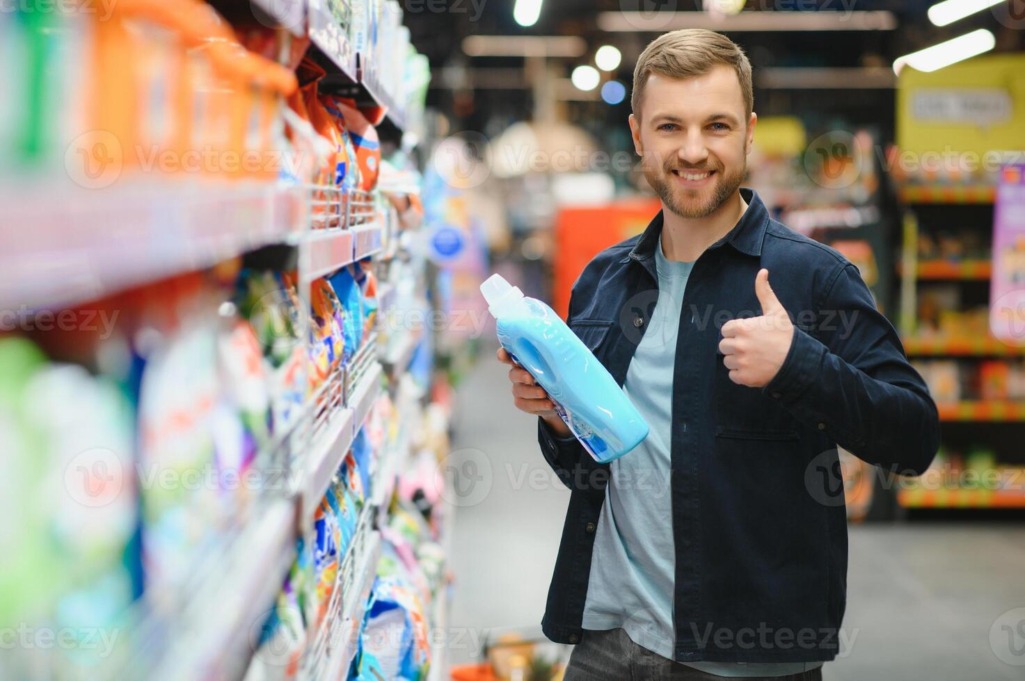 jong vrolijk positief mannetje klant maken aankopen in supermarkt, buying huishouden Chemicaliën foto