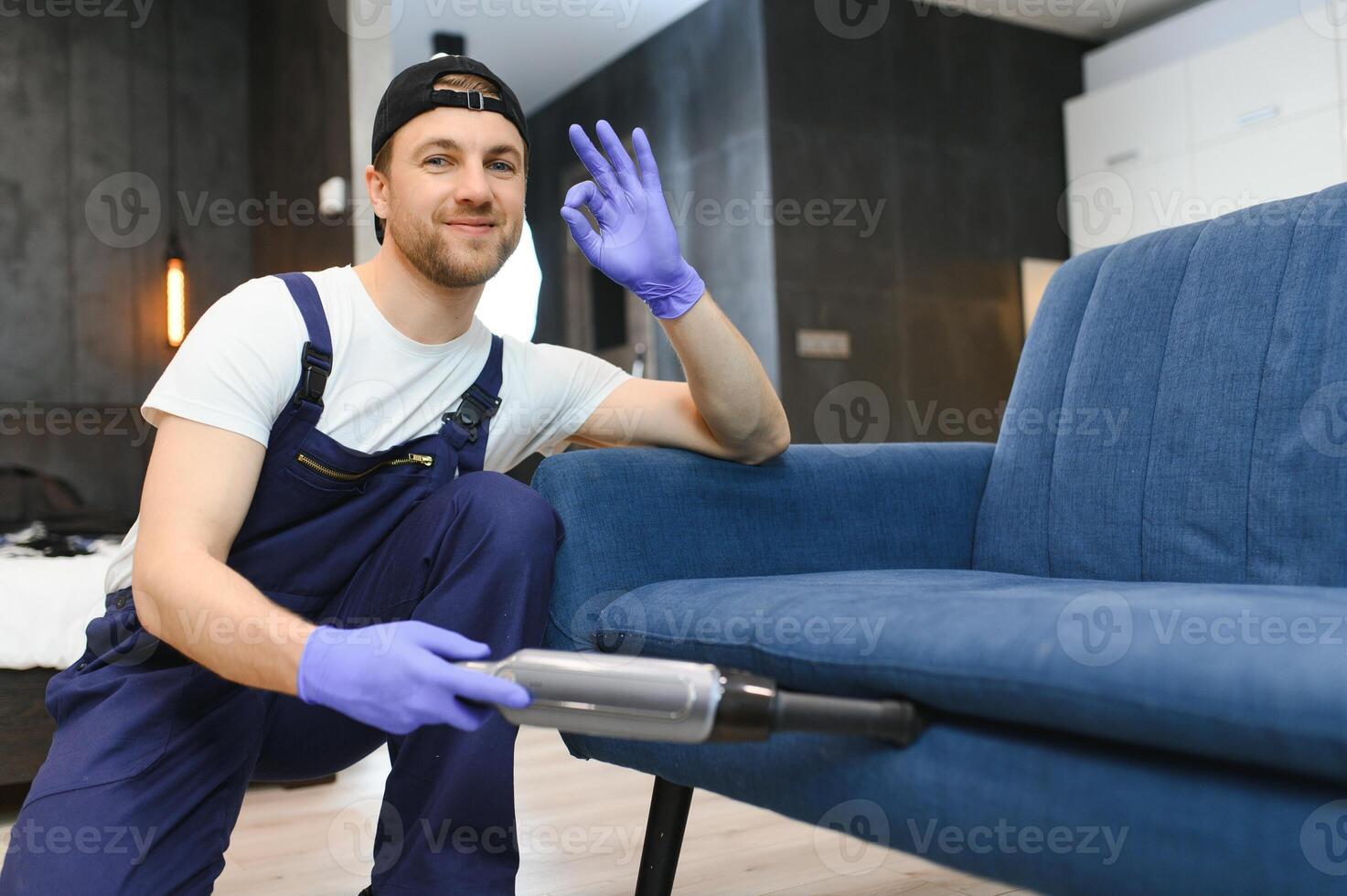 huishoudster Holding modern het wassen vacuüm schoonmaakster en schoonmaak vuil sofa met bekladden met professioneel wasmiddel. professioneel lenteschoonmaak Bij huis concept foto