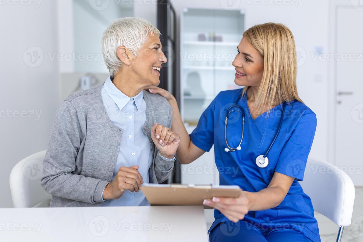 jong vrouw dokter of gp in wit medisch uniform raadplegen vrouw geduldig in privaat ziekenhuis. vrouw therapeut spreken praten met senior vrouw cliënt Aan overleg in kliniek. foto