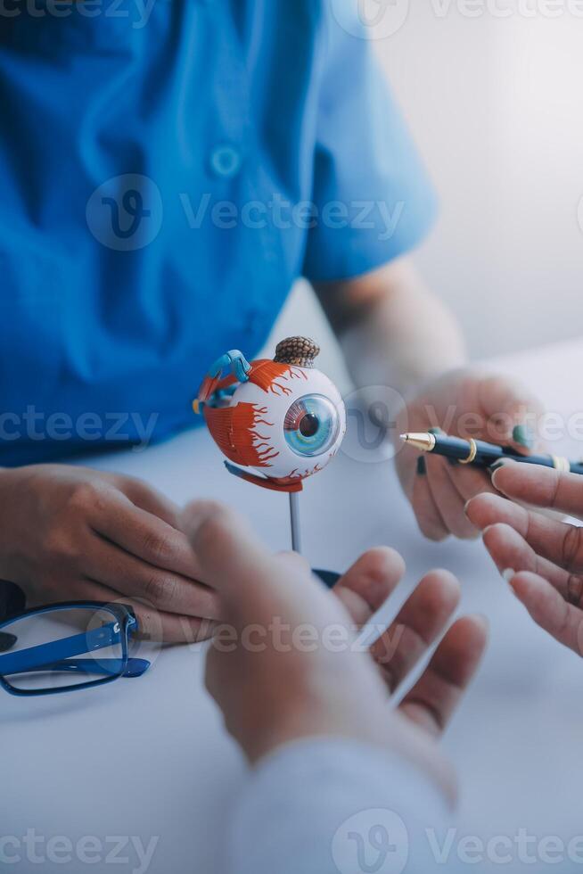 detailopname van Aziatisch vrouw dokter pratend met ouderen geduldig tonen oogbol model- en uitleggen oog ziekte in ziekenhuis foto