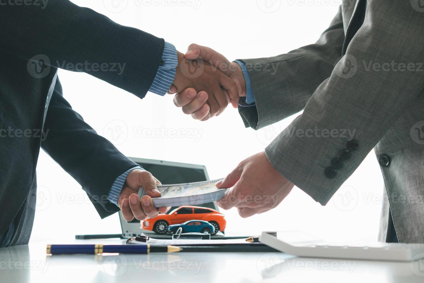 klant en auto handelaar schudden handen na akkoord gaan naar verkoop contract voordat maken contract betaling en overhandigen over- auto sleutels naar klant. concept van handdruk tussen klanten en auto handelaars. foto