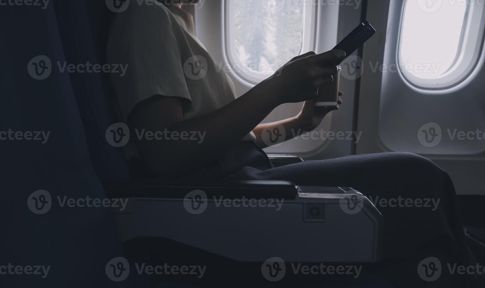 Aziatisch vrouw genieten van geniet een koffie comfortabel vlucht terwijl zittend in de vliegtuig cabine, passagiers in de buurt de venster. foto