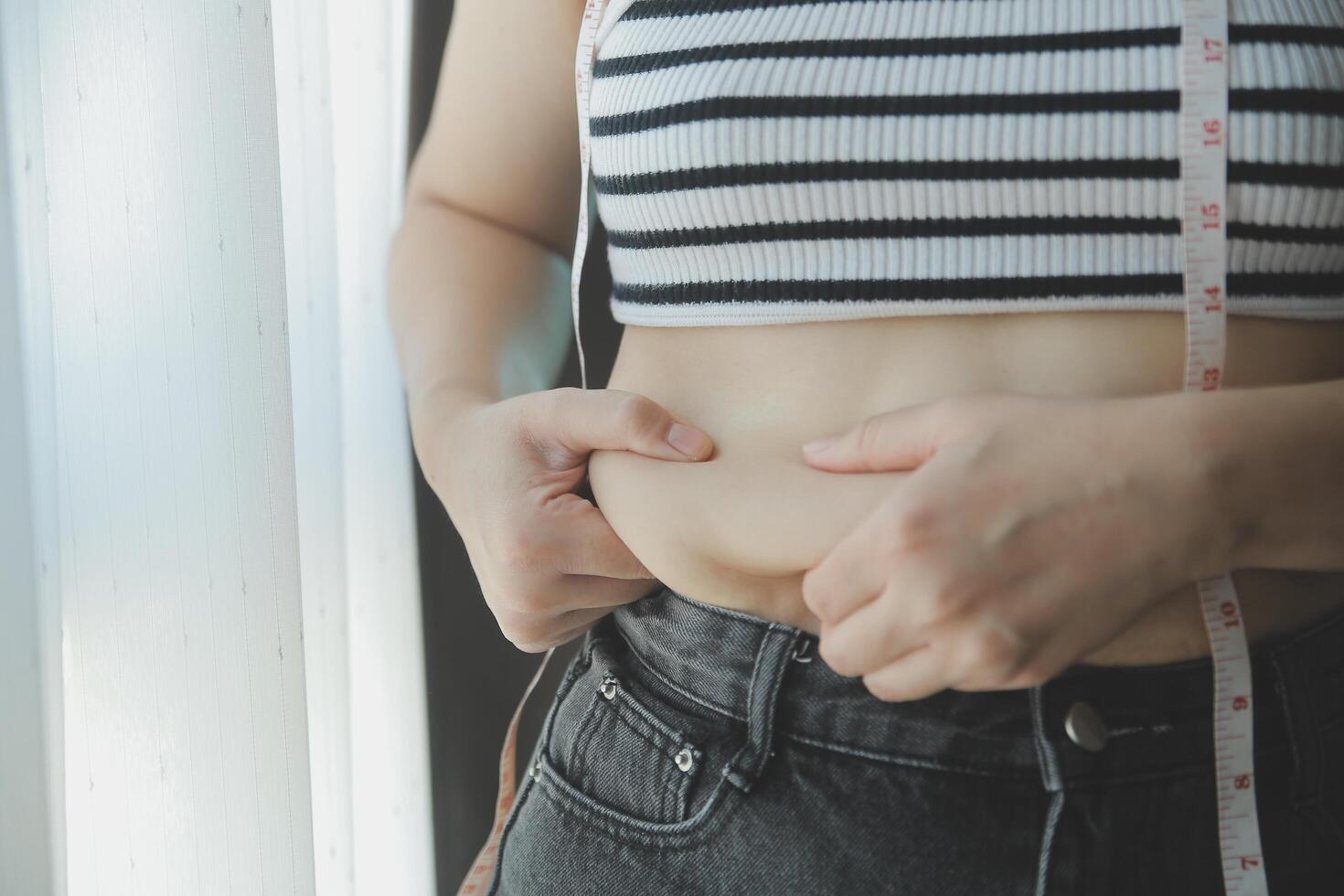 Dames lichaam dik buik. zwaarlijvig vrouw hand- Holding buitensporig buik dik. eetpatroon levensstijl concept naar verminderen buik en vorm omhoog gezond maag spier. foto