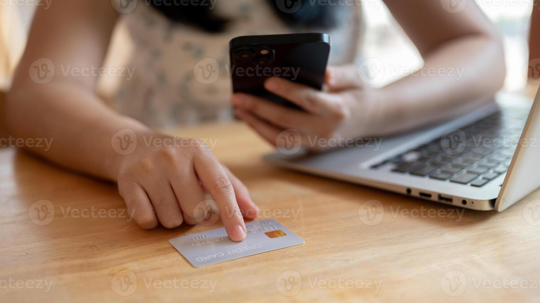 een detailopname beeld van een Aziatisch vrouw richten haar vinger Bij een credit kaart Aan de tafel. foto
