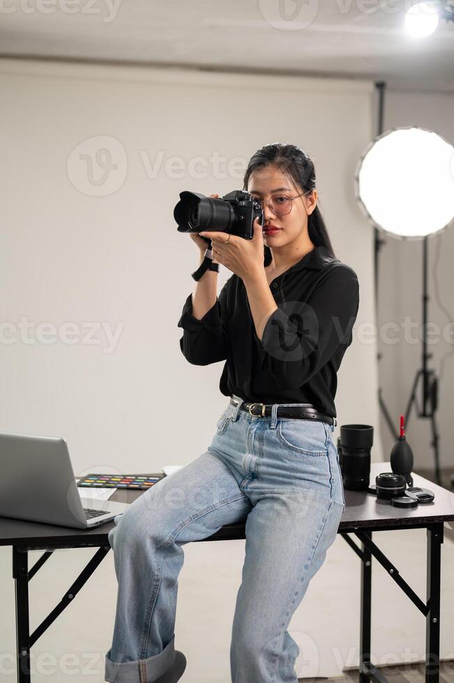 een vrouw fotograaf is nemen foto's, Holding een camera in de buurt haar gezicht, werken in een studio. foto