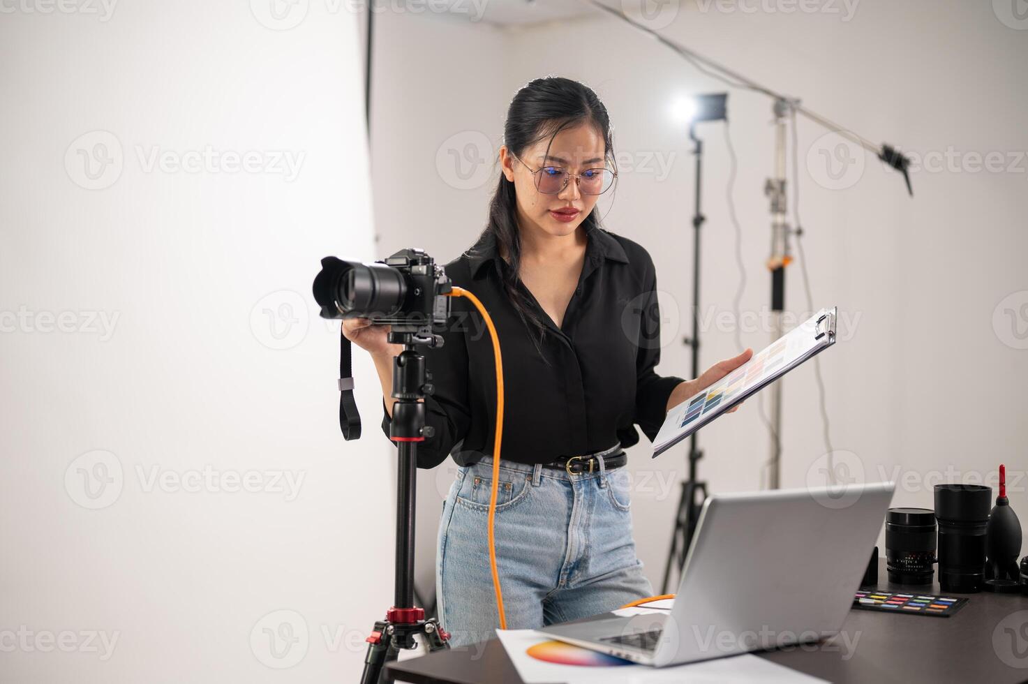een koel, aantrekkelijk Aziatisch vrouw fotograaf producent is werken in een het schieten studio. foto