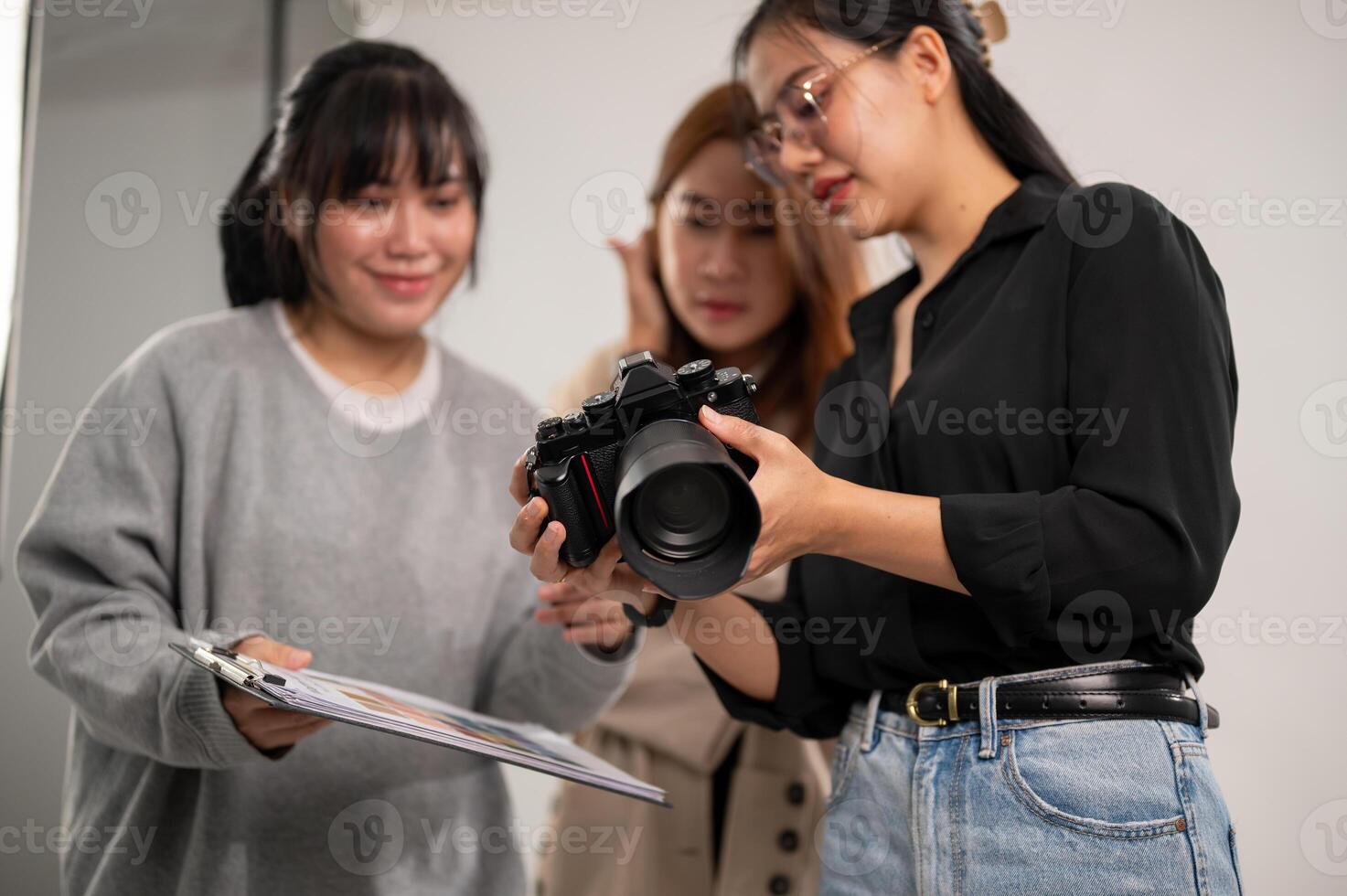 een fotograaf is tonen afbeeldingen Aan haar camera naar kunst regisseurs, werken met haar team in de studio foto