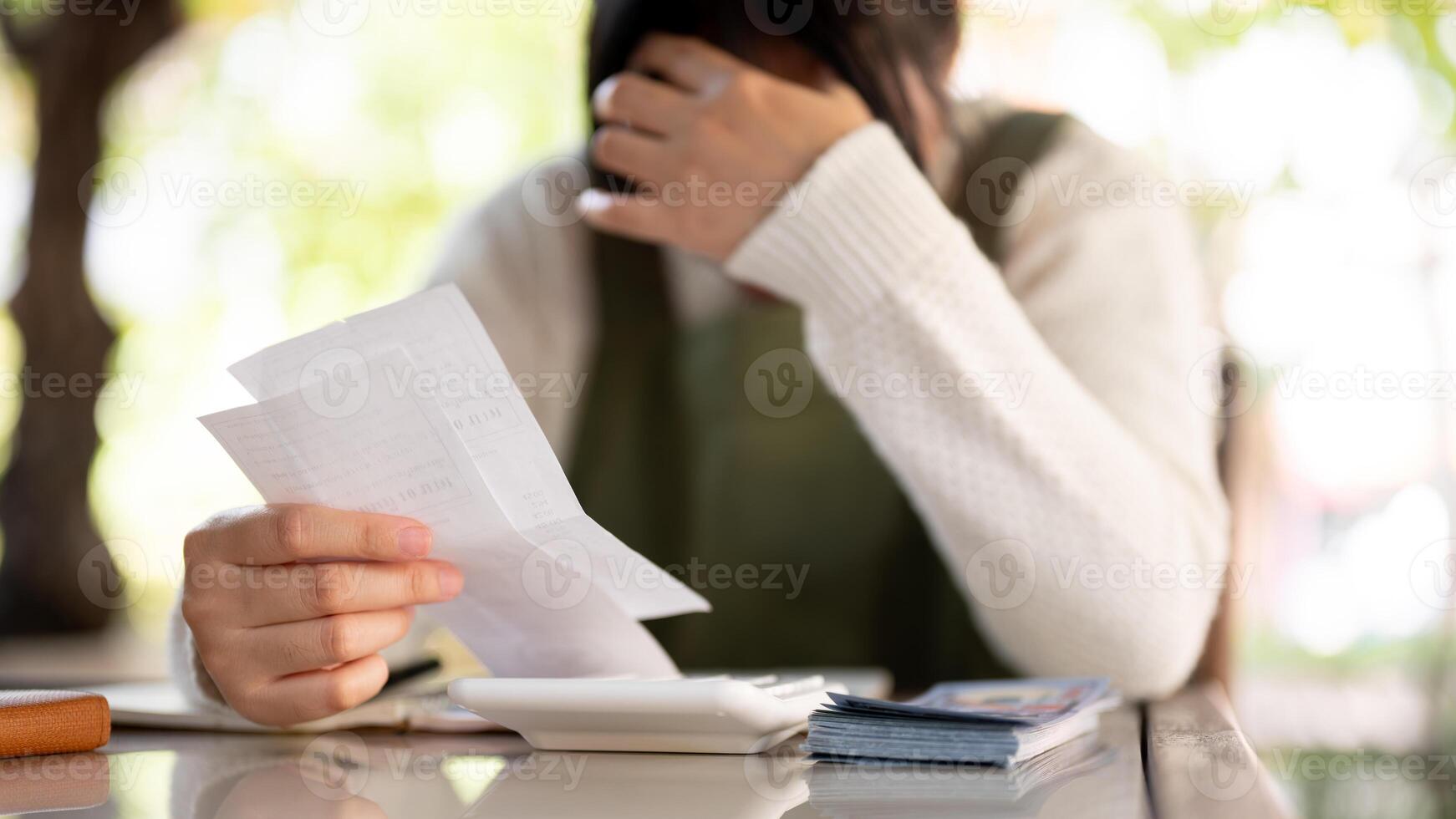 een benadrukt Aziatisch vrouw klein bedrijf eigenaar is berekenen rekeningen, bezorgd over haar winkel uitgaven. foto