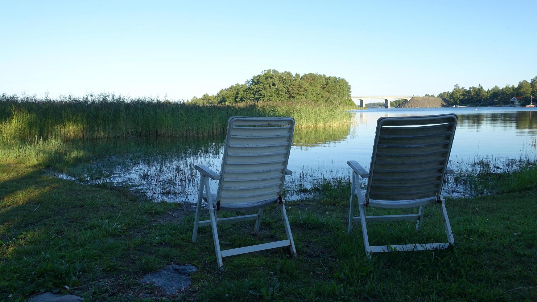 twee plastic stoelen door de meer Aan een zomer middag foto