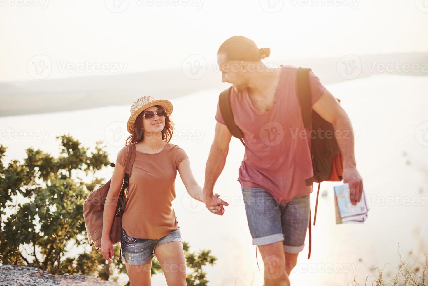 blij zijn. jong stel heeft besloten om hun vakantie actief door te brengen aan de rand van de prachtige rots met meer op de achtergrond foto