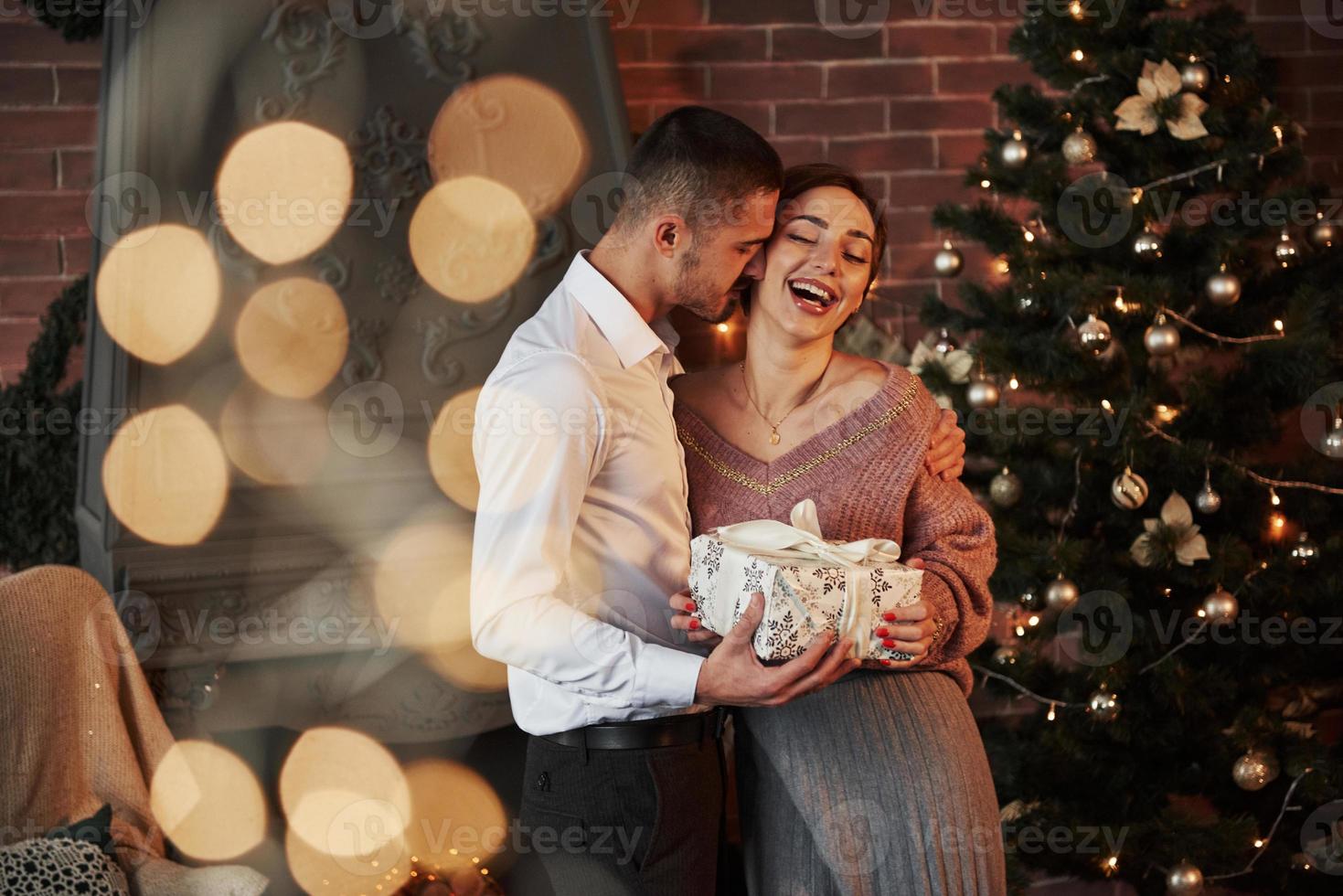 nieuwjaar geluk. kerstcadeau voor de vrouw. heer in klassiek pak geeft zijn vrouw het cadeau foto