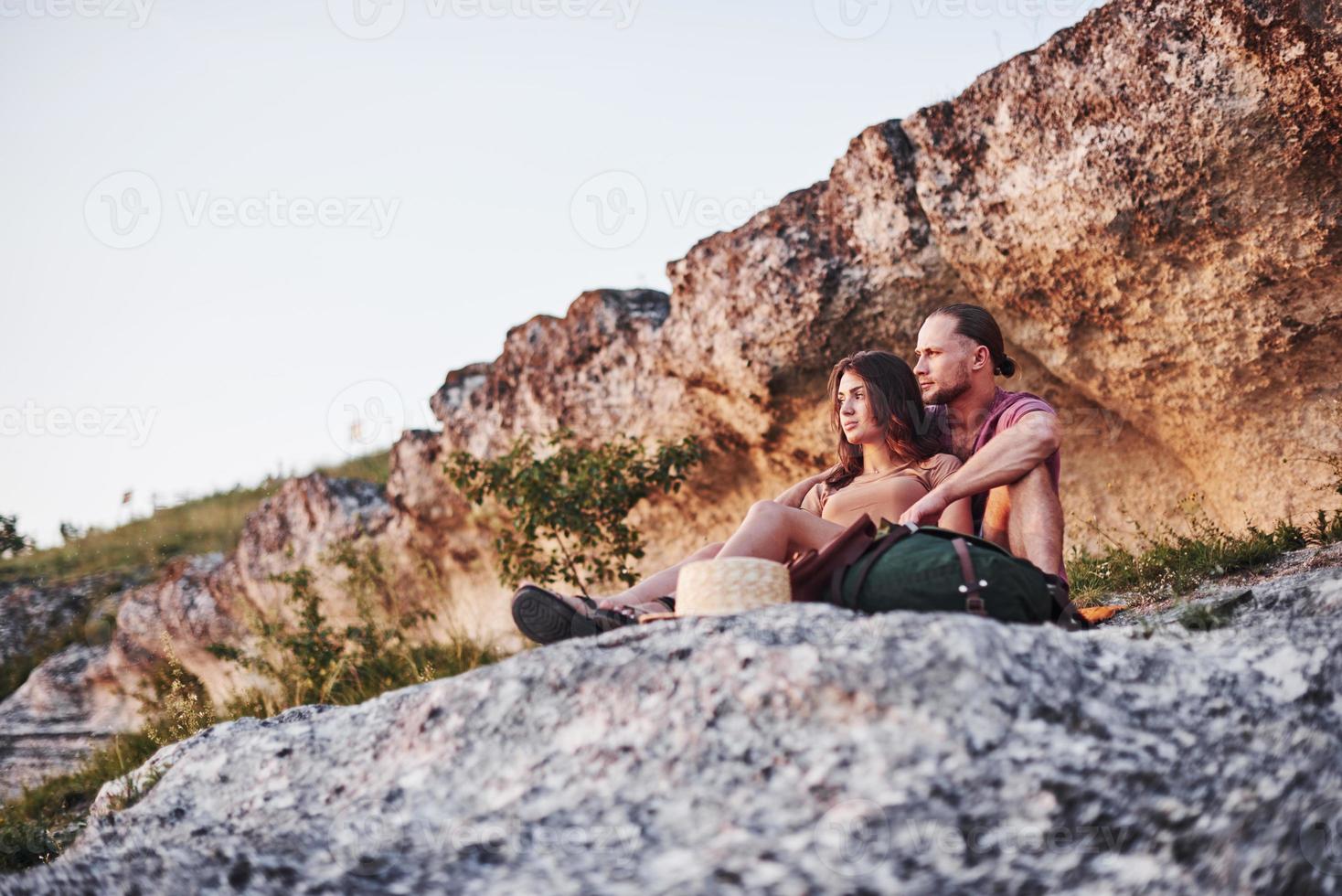 dromende stemming. twee personen zittend op de rots en kijken naar de prachtige natuur foto