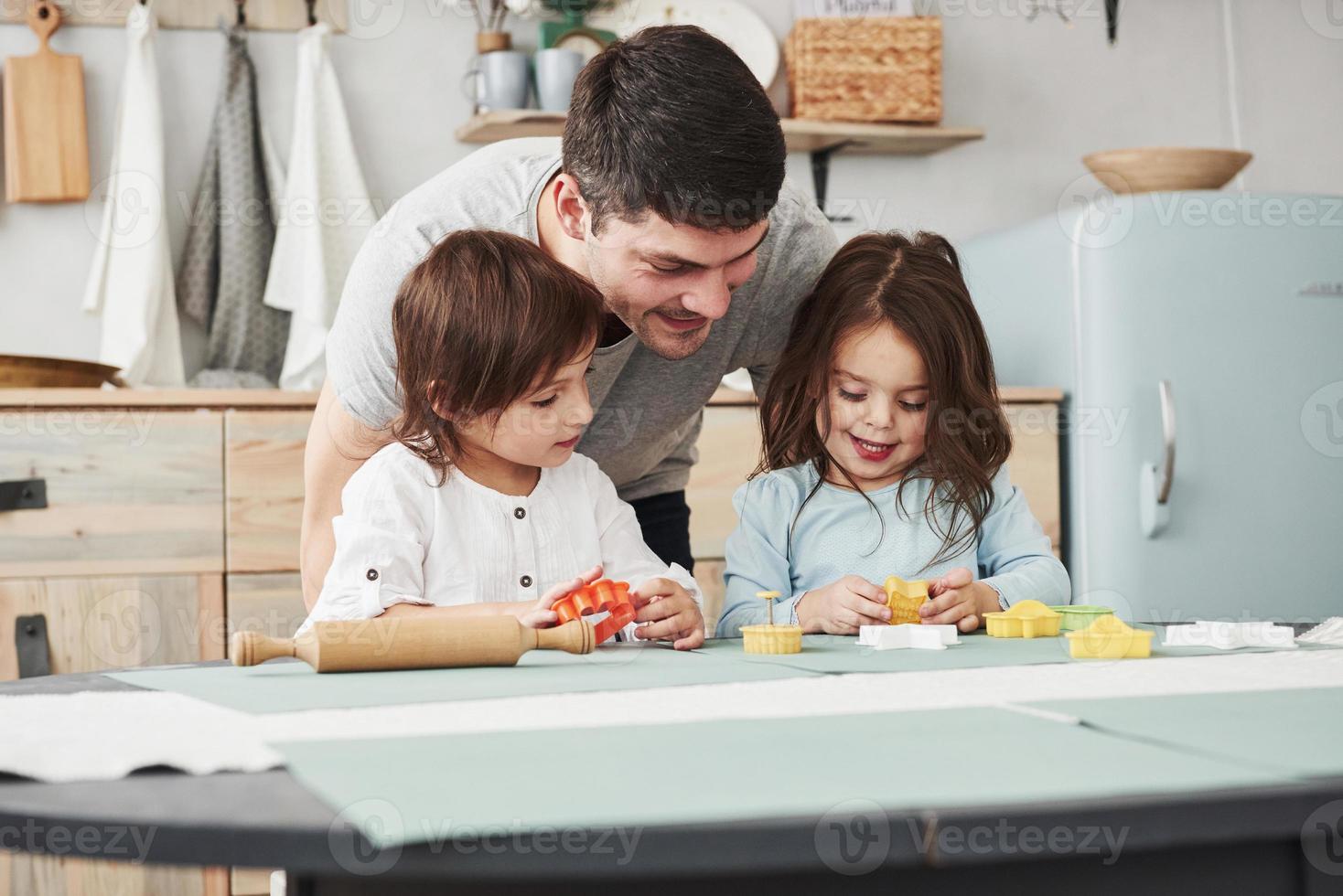 vader speelt met twee meisjes in de keuken. conceptie van ouderschap foto