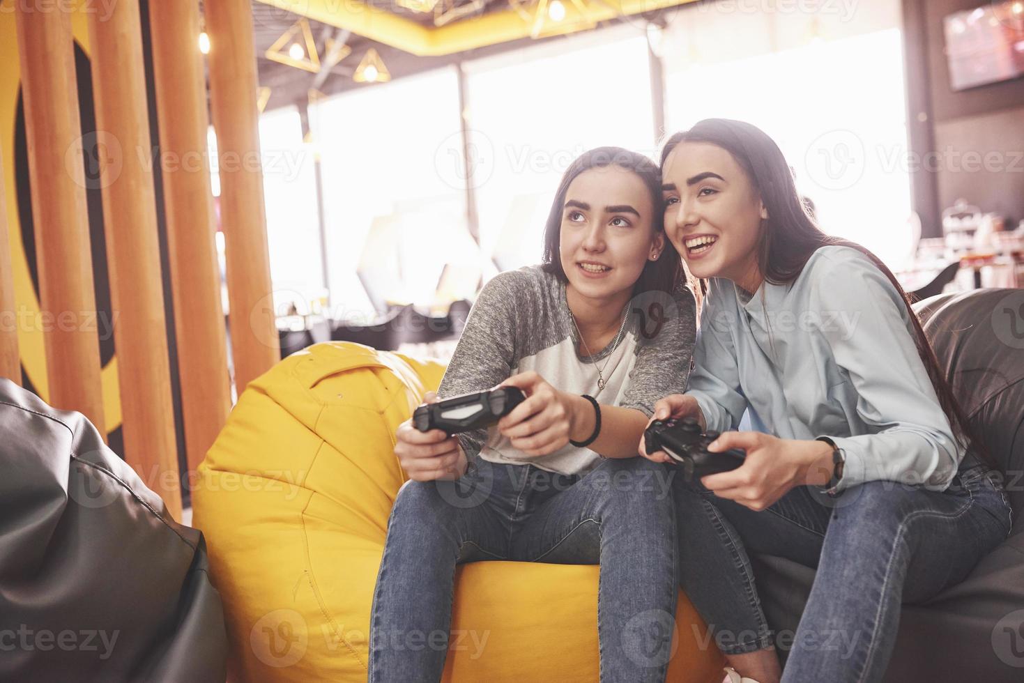 tweelingzusjes spelen op de console. meisjes houden joysticks in hun handen en hebben plezier foto