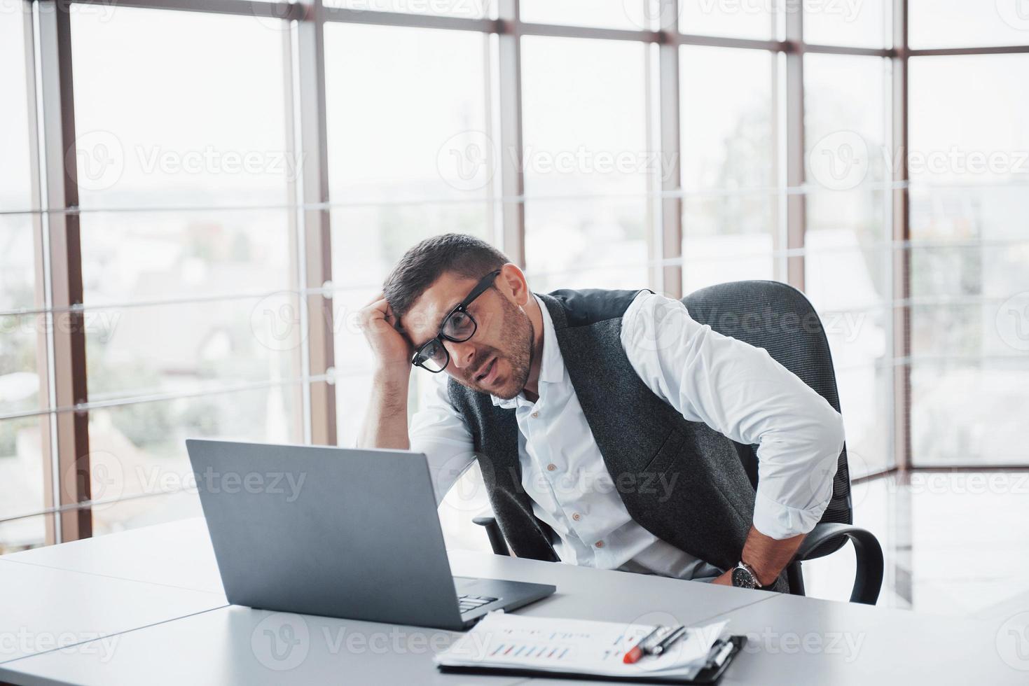 werknemer is een jonge man met een laptop op kantoor foto