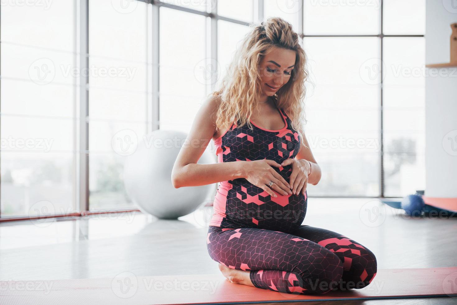 concept van yoga en fitness zwangerschap. portret van een jong model van een zwangere vrouw die zich binnenshuis ontwikkelt. foto