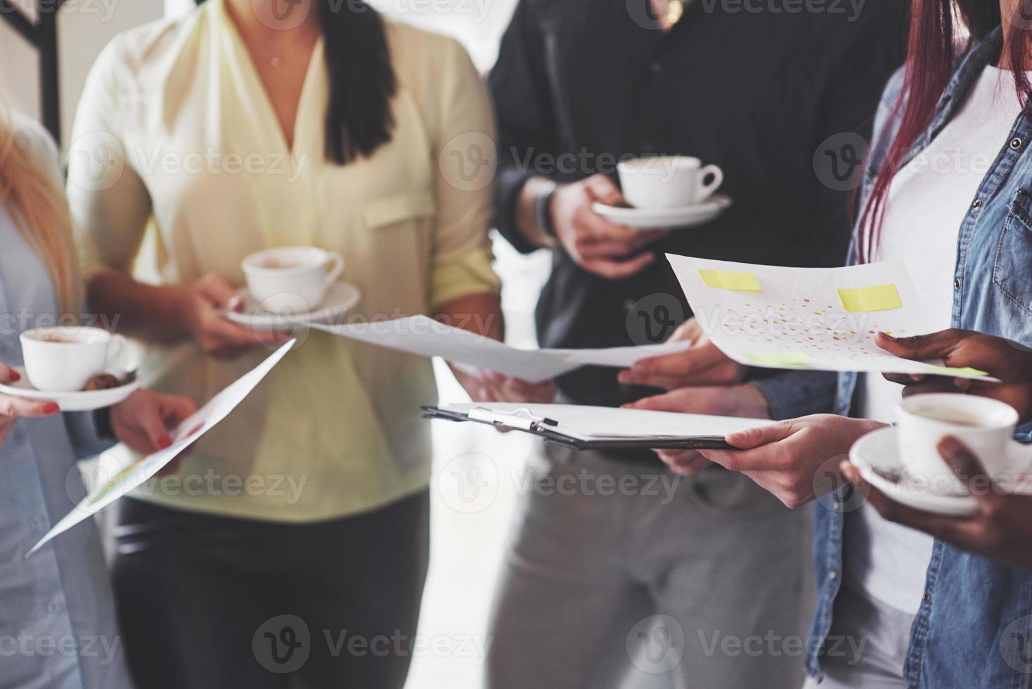 succesvolle jonge zakenmensen praten en glimlachen tijdens de koffiepauze op kantoor foto