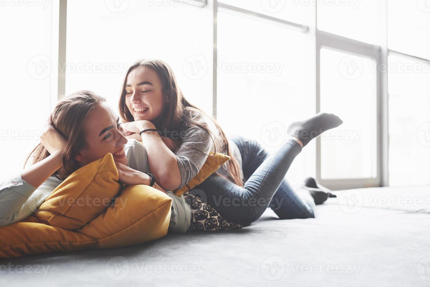 twee mooie jonge tweelingzusjes die tijd doorbrengen samen met kussens. broers en zussen met plezier thuis concept foto