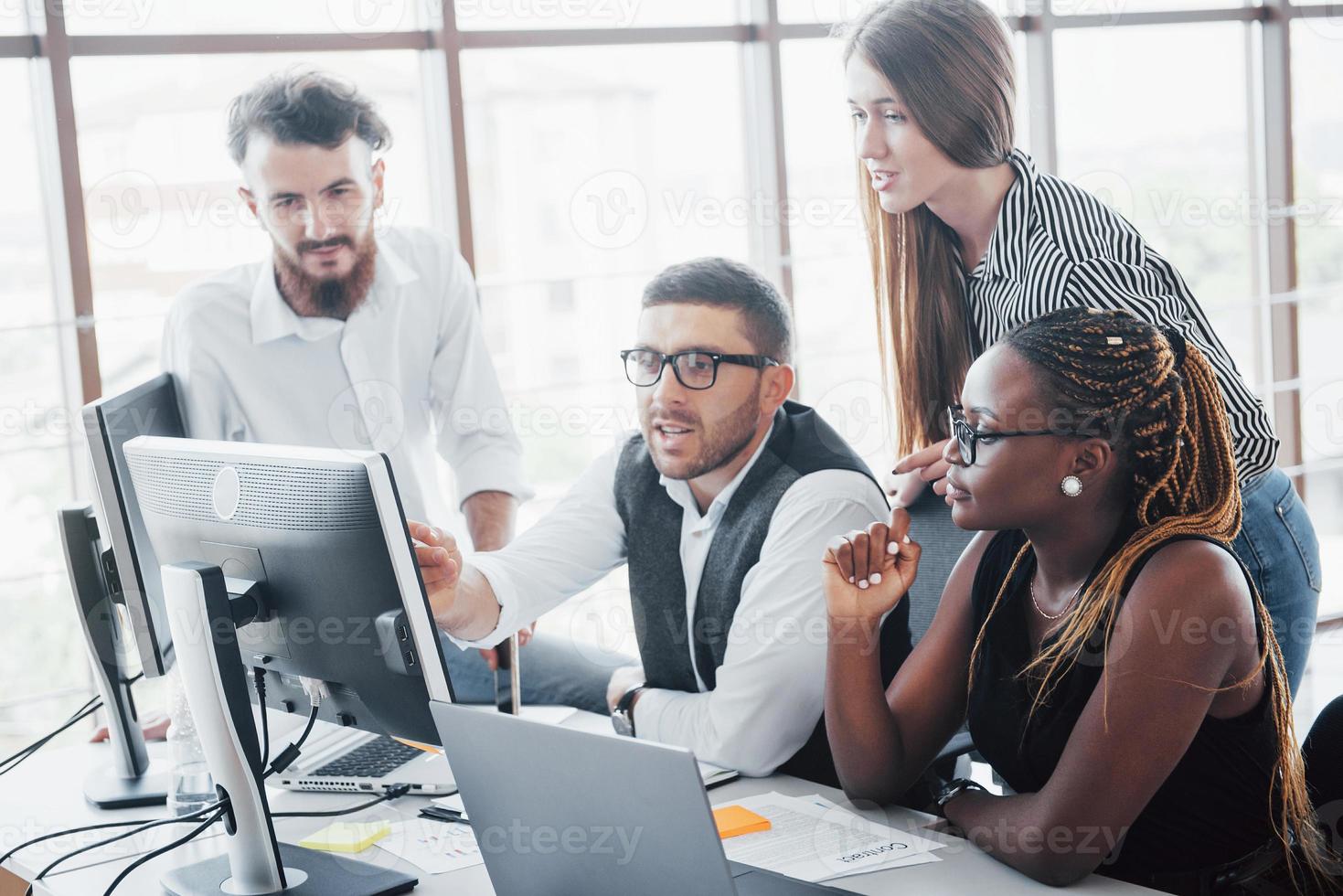 jonge werknemers die op kantoor aan tafel zitten en een laptop gebruiken, een brainstorming-vergaderingsconcept voor teamwerk. foto