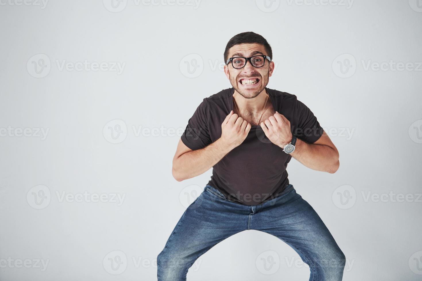 emotionele man in vrijetijdskleding en met een bril houdt zichzelf vast aan de kraag van een t-shirt en is klaar om het aan zichzelf te verscheuren foto