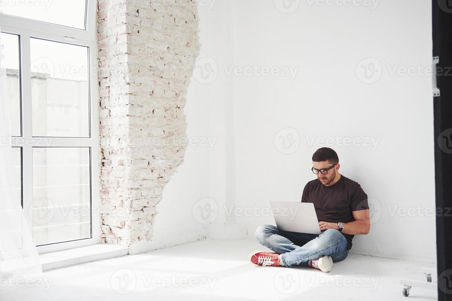 knappe jonge man met laptop en controleer zijn tijdschema op witte achtergrond foto