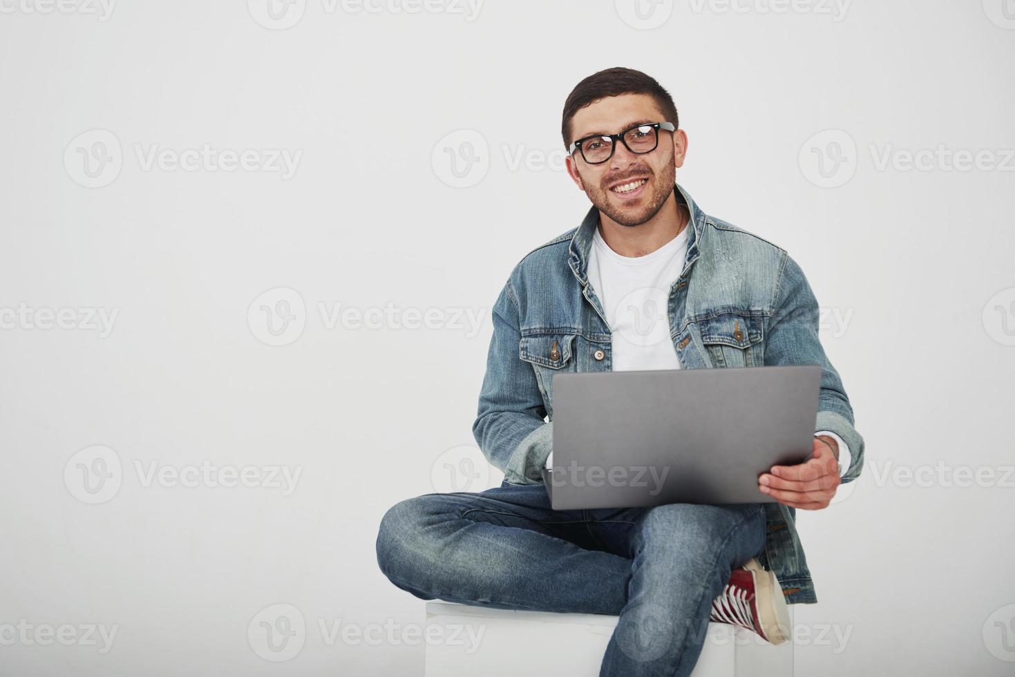 knappe jonge man met laptop en controleer zijn tijdschema op witte achtergrond foto