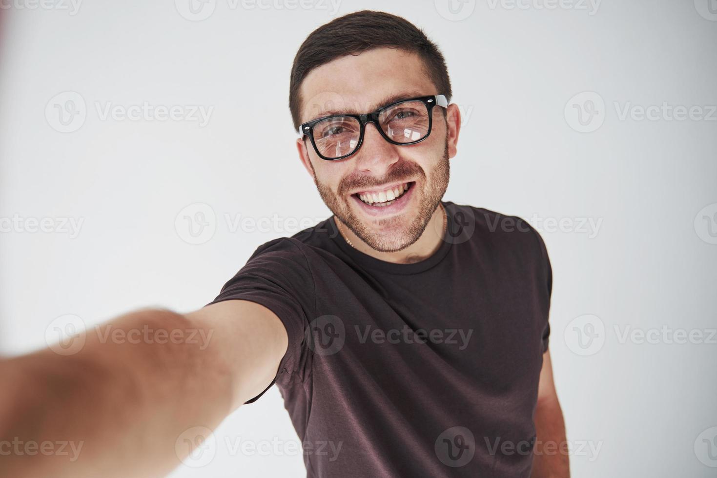 Jonge hipster kerel die een bril draagt die gelukkig lacht geïsoleerd op een witte achtergrond foto