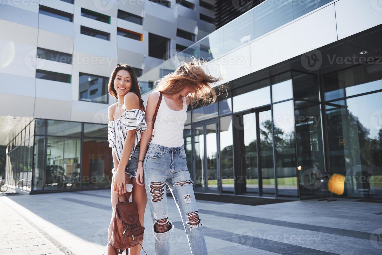 twee mooie gelukkige jonge student meisje met rugzak in de buurt van de campus van de universiteit. onderwijs en vrije tijd concept foto