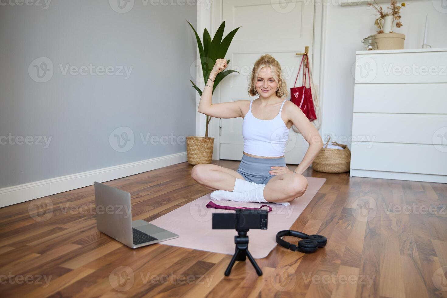 portret van jong geschiktheid instructeur, vlogger tonen opdrachten Aan camera, opname haarzelf, zittend Aan mat met laptop, aan het doen training, uitleggen yoga bewegingen naar volgers foto