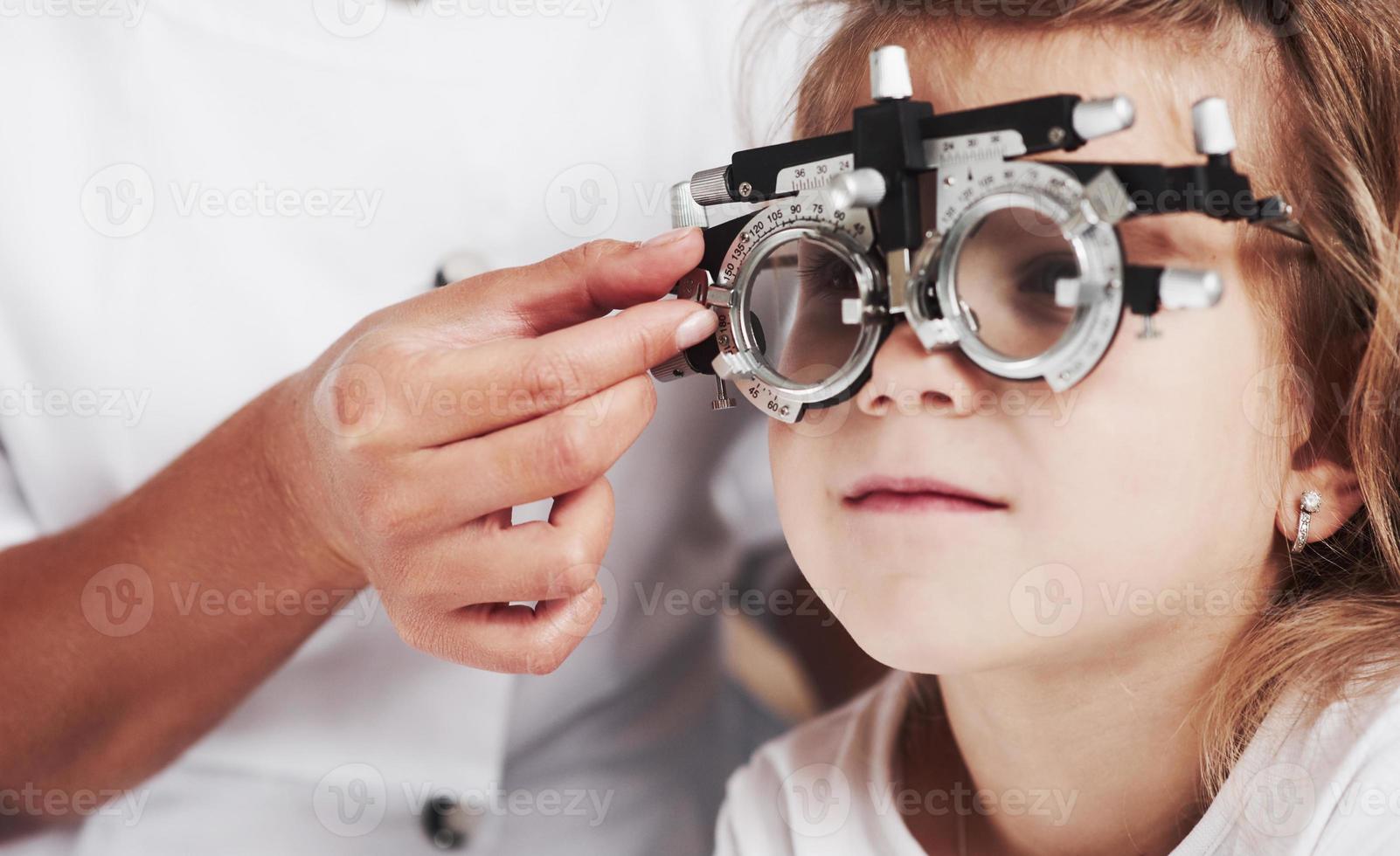 close-up foto. dokter controleert het zicht van het meisje en stemt de phoropter af foto