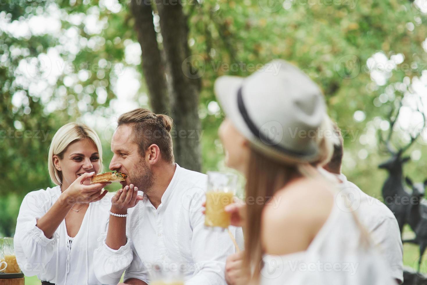 vrouw voedt haar man overdag met een heerlijk broodje buiten met vrienden foto