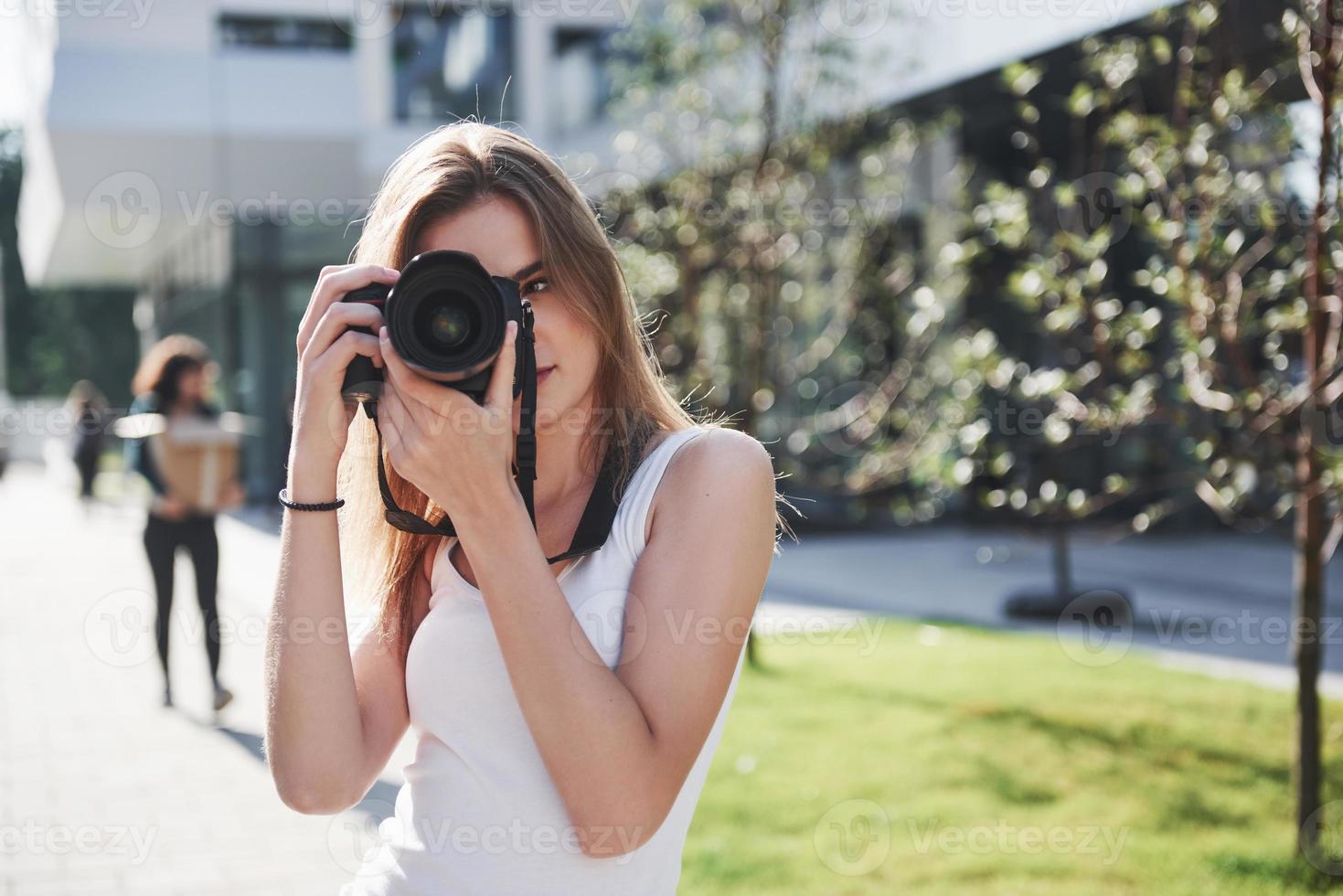 meisjesfotograafblogger houdt een professionele camera in de hand in de open lucht in de stad foto