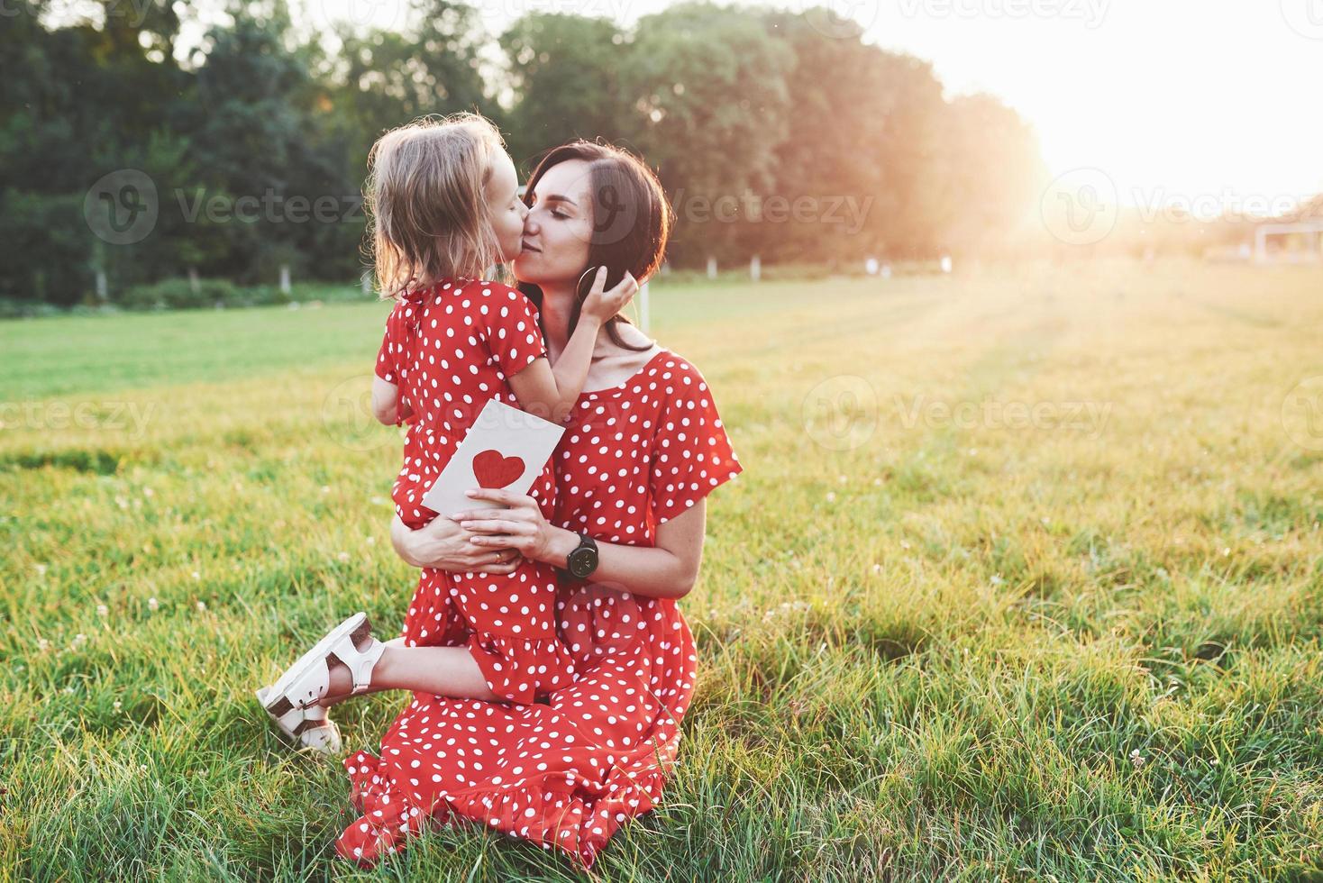 moeder met papieren boek en meisje in haar handen en geef haar een kus foto