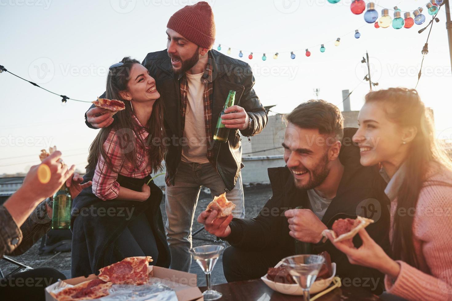 vreugde en lachen. pizza eten op het dakfeest. goede vrienden hebben weekend met lekker eten en alcohol foto