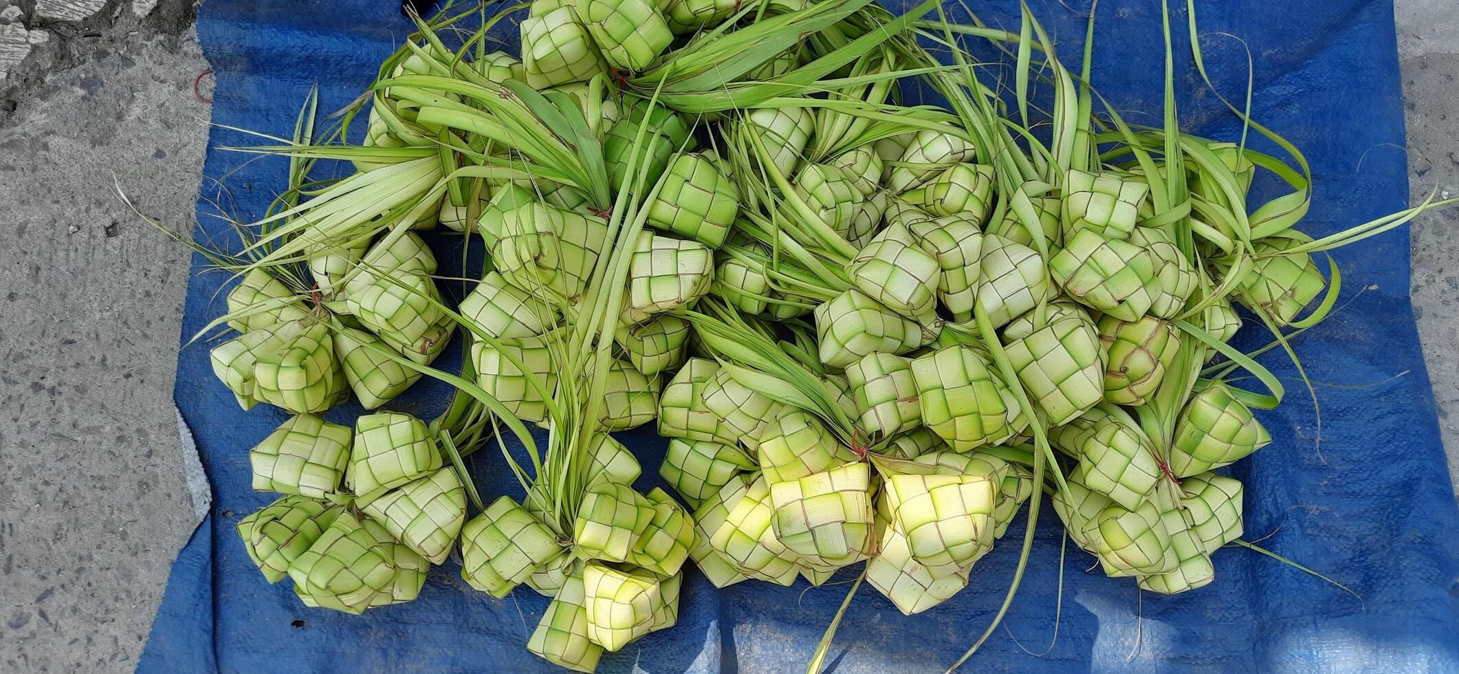 ketupat of rijst- knoedel. een traditioneel rijst- behuizing gemaakt van jong kokosnoot bladeren voor Koken rijst- verkocht in traditioneel markt voorbereiding voor de eid al-fitr vakantie voor moslim foto