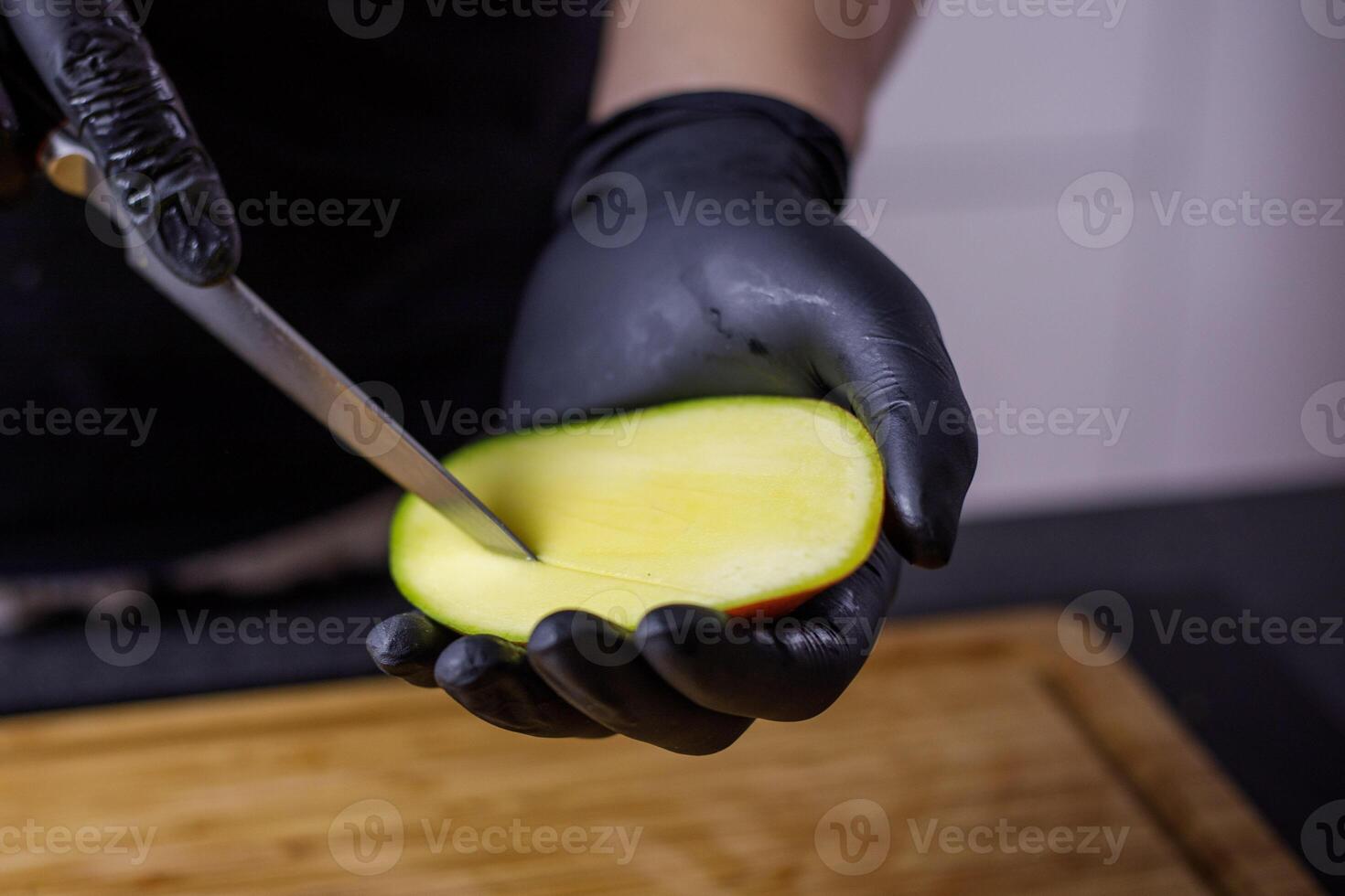 persoon met zwart handschoenen snijdend en snijden mango voor smoothie hout snijdend foto