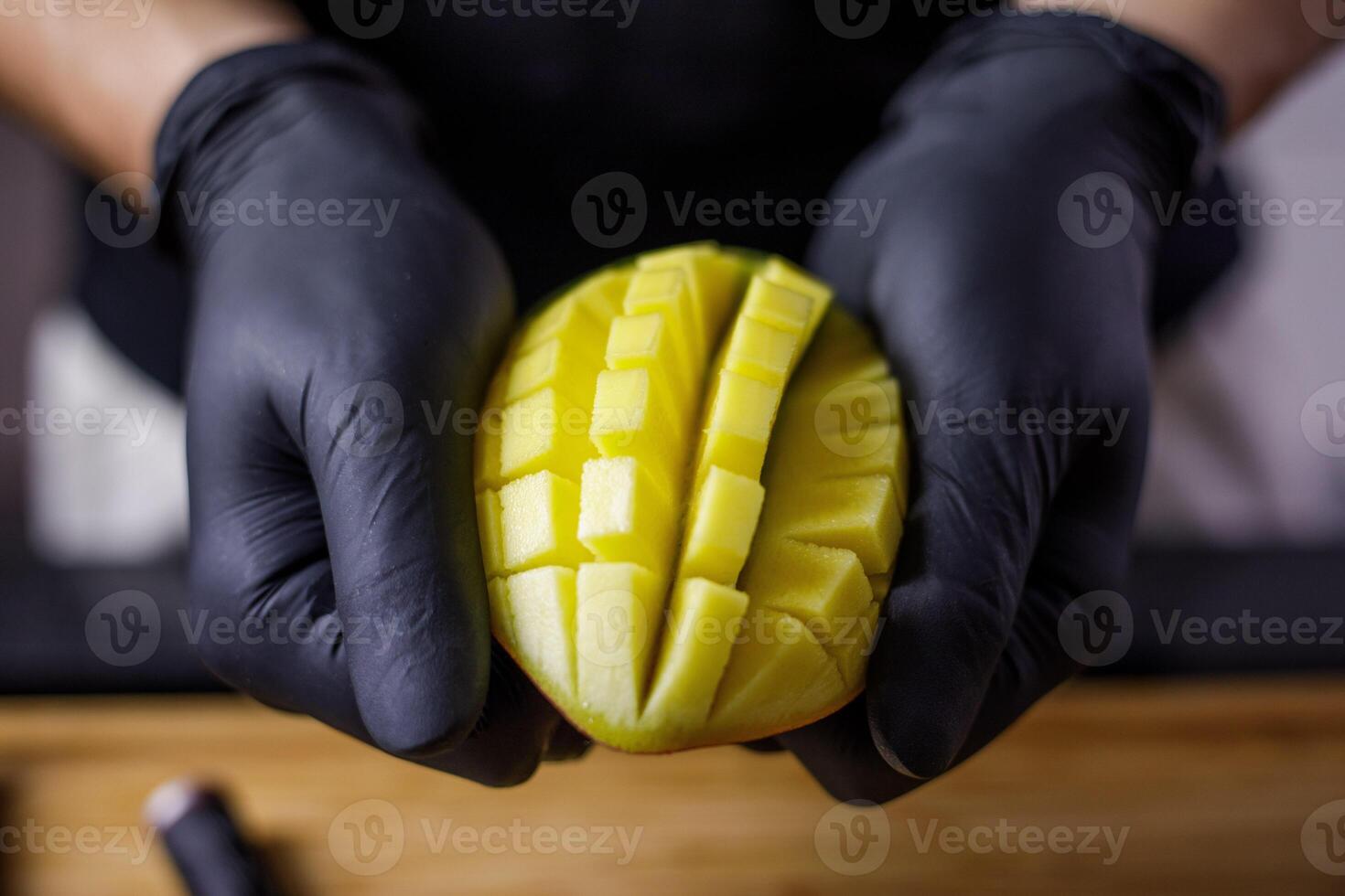 persoon met zwart handschoenen snijdend en snijden mango voor smoothie hout snijdend foto