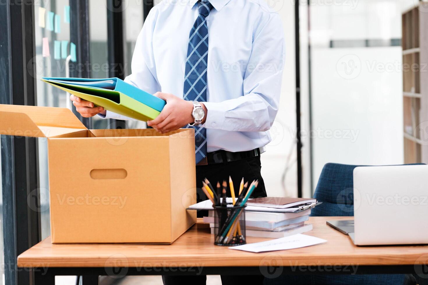 een Mens in een pak is opening een karton doos Aan een bureau foto