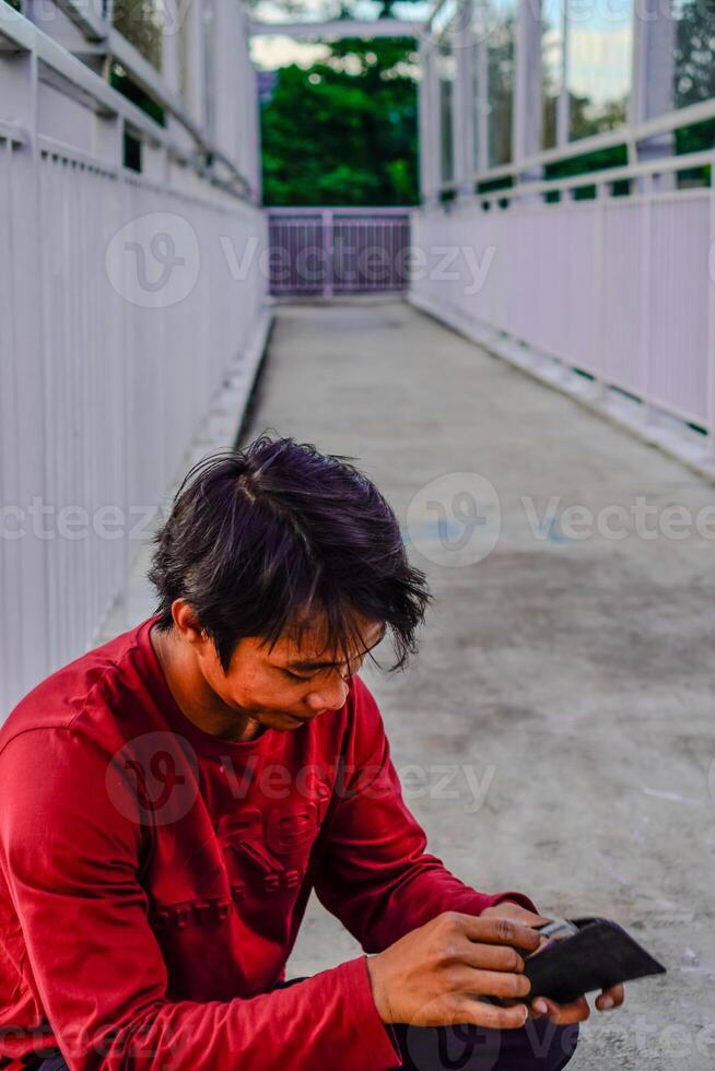 de Mens in rood is op zoek Bij de inhoud van de portemonnee. foto