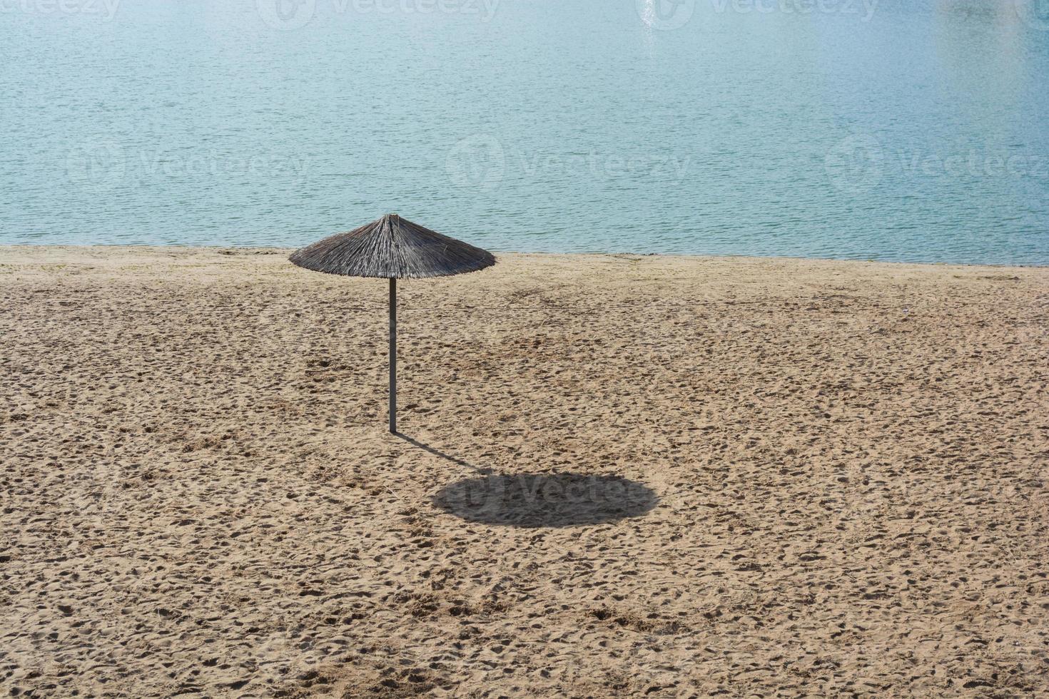 een rieten paraplu op een leeg strand 's middags. foto