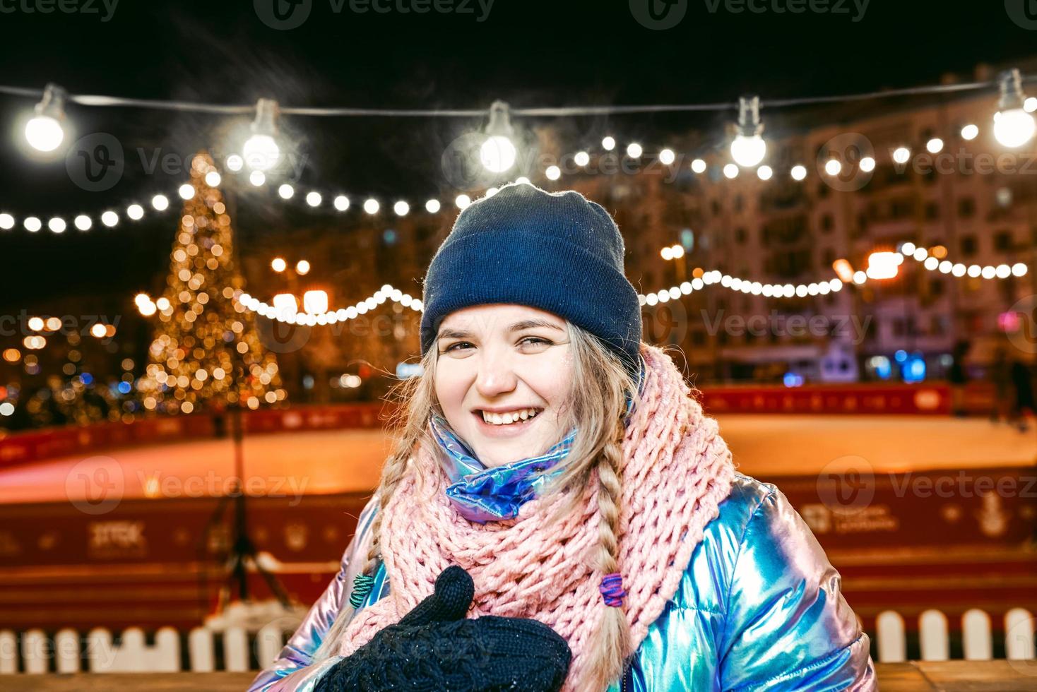 gelukkig lachende jonge blanke vrouw in sjaal, muts, jas, wanten door de buitenbaan. nieuwjaar, plezier, winterconcept foto