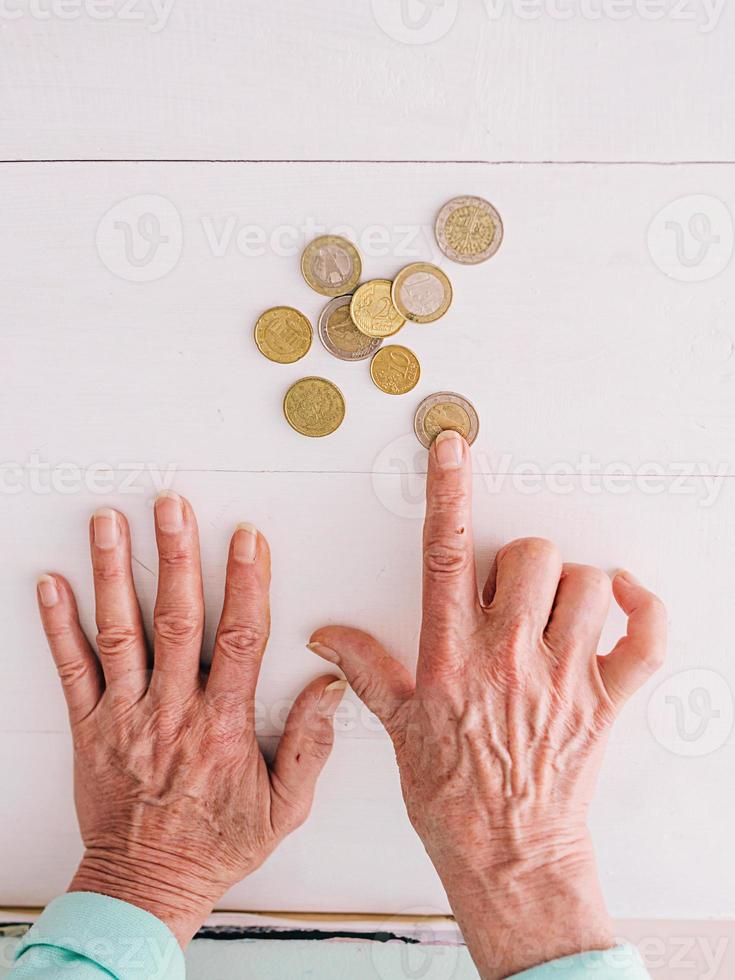 senior handen tellen euromunten op tafel. armoede, crisis, storting, recessieconcept foto