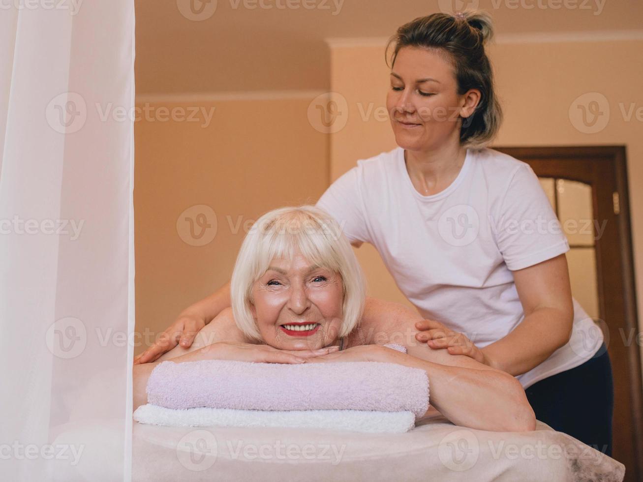 oudere kaukasische stijlvolle vrouw met grijs haar dat een massage oplegt. anti-leeftijd, gezonde levensstijl, massageconcept foto