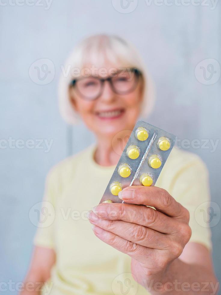 senior lachende vrouw met pillen in haar hand. gezondheidszorg, medisch, behandeling, leeftijdsconcept foto