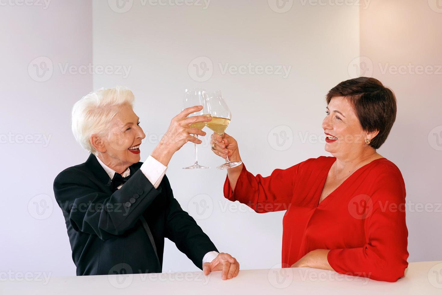 twee mooie stijlvolle volwassen senior vrouwen die wijn drinken in de bar. plezier, feest, stijl, feest foto