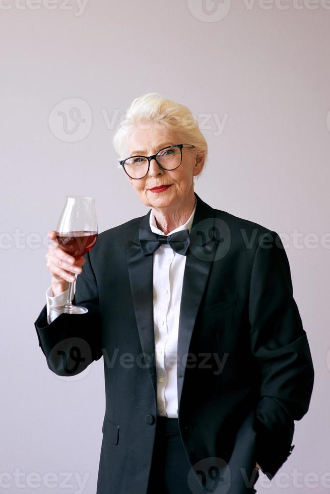 stijlvolle volwassen sommelier senior vrouw in smoking met glas wijn. plezier, feest, stijl, levensstijl, werk, alcohol, feestconcept foto