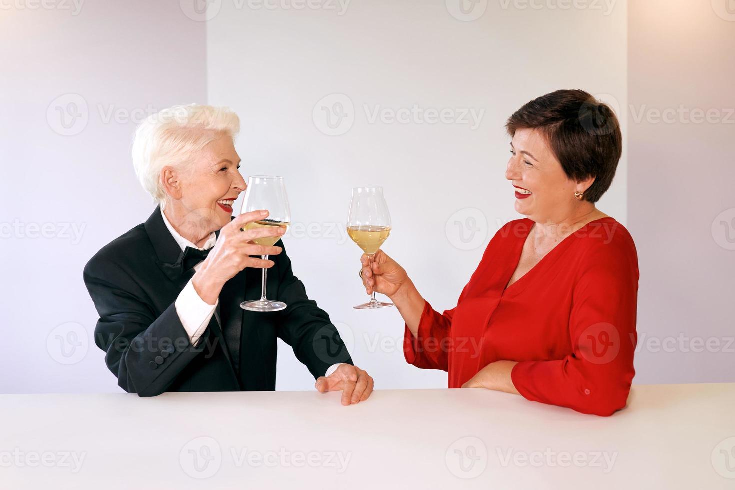 twee mooie stijlvolle volwassen senior vrouwen die wijn drinken in de bar. plezier, feest, stijl, feest foto