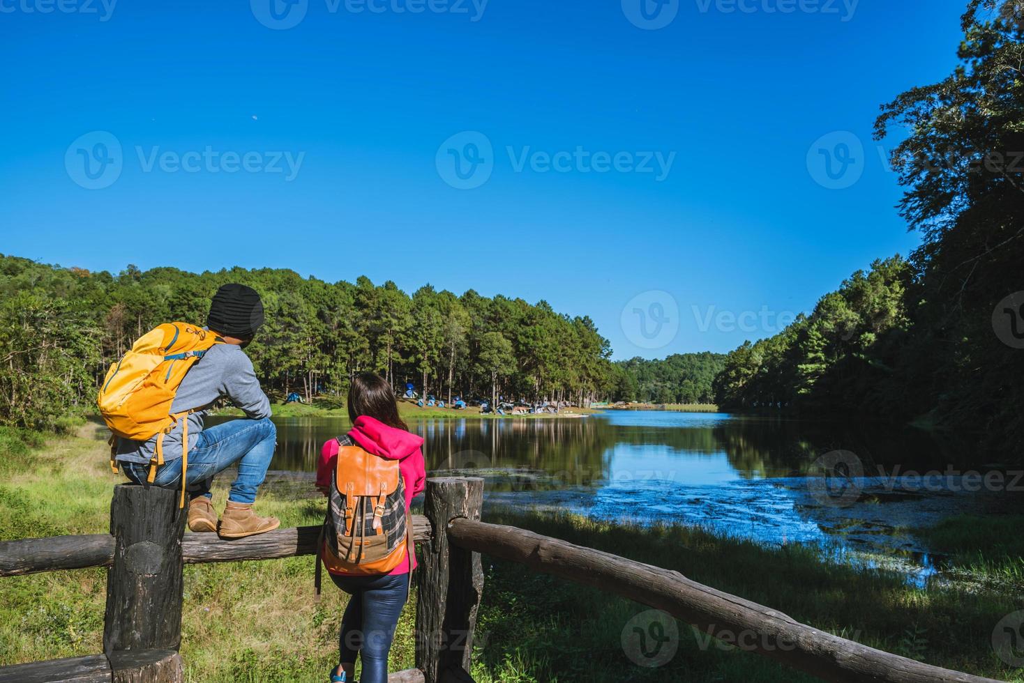 een paar reizigers met rugzak staan op de top van het uitkijkpunt, de natuur is prachtig, geniet van de zonsopgang op het mistige oppervlak van het meer, jonge mannen en aziatische vriendinnen reizen door de natuur foto