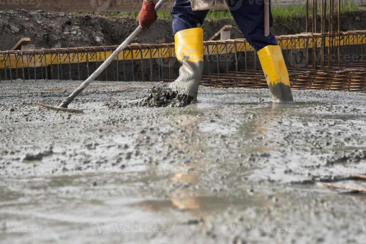 metselaar die het vers gestorte beton egaliseert om de fundamenten van een gebouw te leggen foto