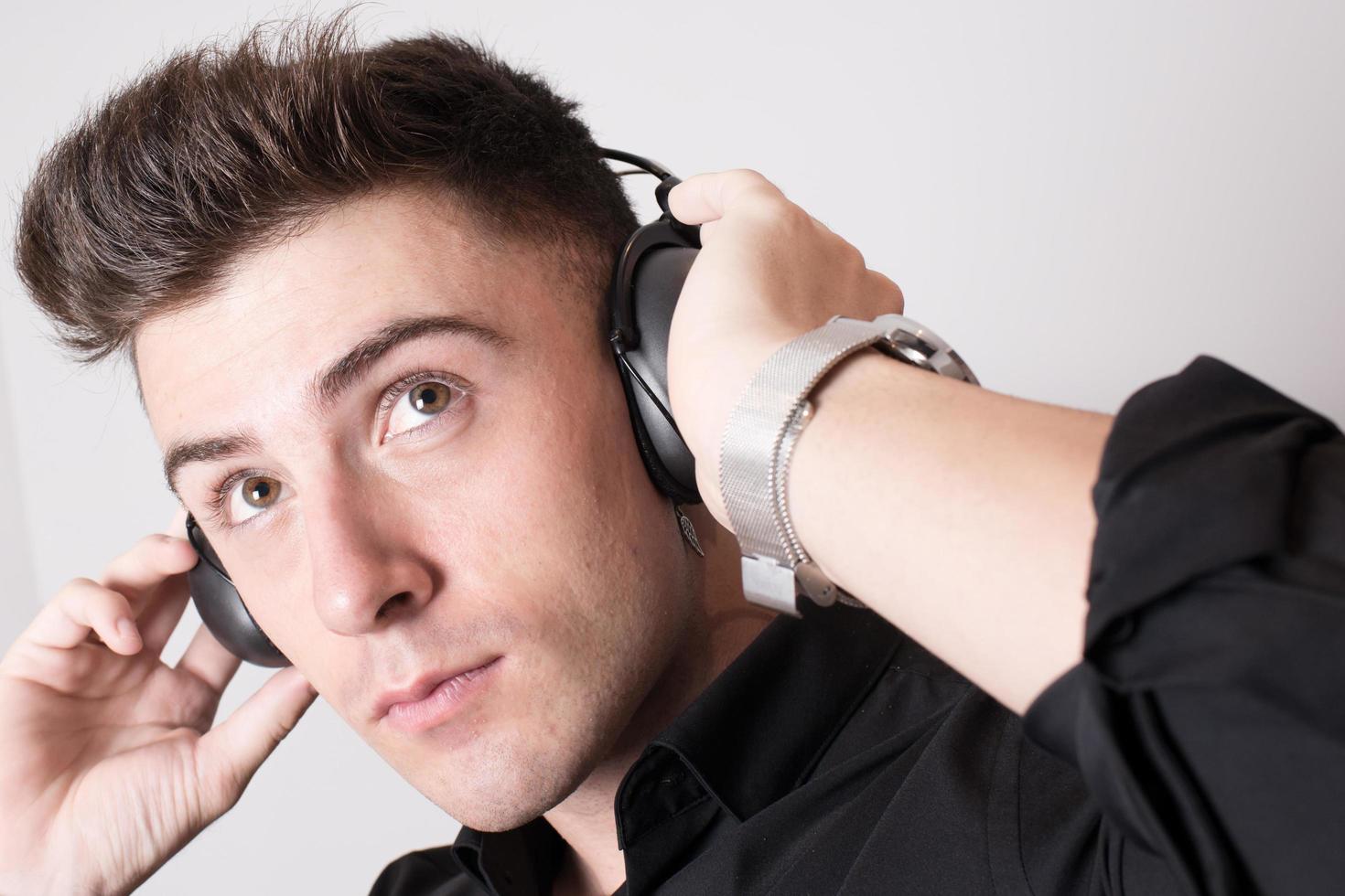 close-up van een aantrekkelijke jonge man met zwarte koptelefoon terwijl hij naar muziek luistert foto